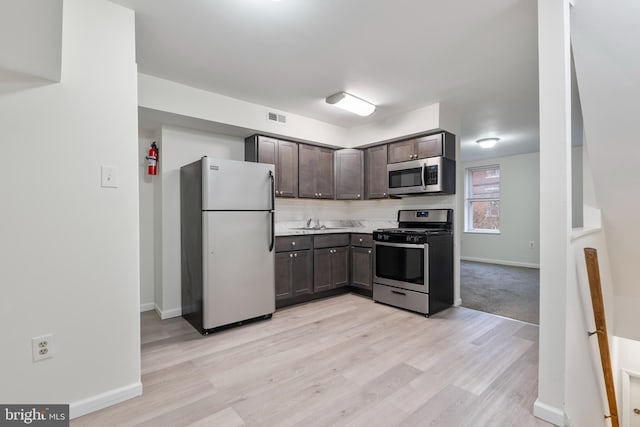 kitchen with sink, light wood-type flooring, dark brown cabinetry, and stainless steel appliances