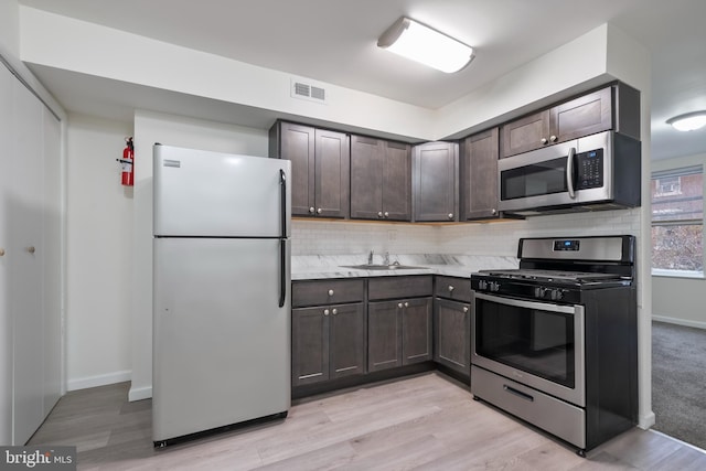 kitchen with backsplash, sink, light hardwood / wood-style flooring, and appliances with stainless steel finishes