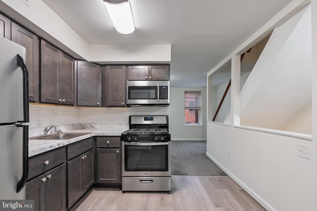 kitchen featuring appliances with stainless steel finishes, tasteful backsplash, light hardwood / wood-style flooring, and dark brown cabinets