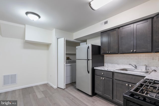 kitchen with tasteful backsplash, dark brown cabinets, stainless steel appliances, sink, and light hardwood / wood-style flooring