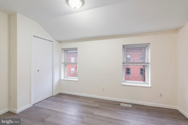 spare room with light hardwood / wood-style flooring and vaulted ceiling