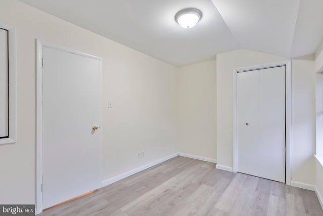 unfurnished bedroom with a closet, light hardwood / wood-style floors, and lofted ceiling