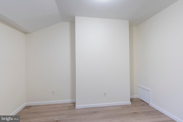 spare room with light hardwood / wood-style floors and vaulted ceiling