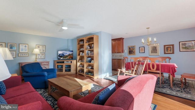 living room with light hardwood / wood-style floors and ceiling fan with notable chandelier