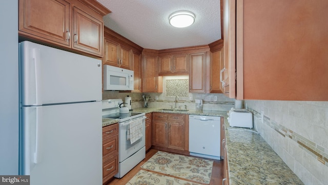 kitchen with light stone countertops, white appliances, light hardwood / wood-style floors, and sink