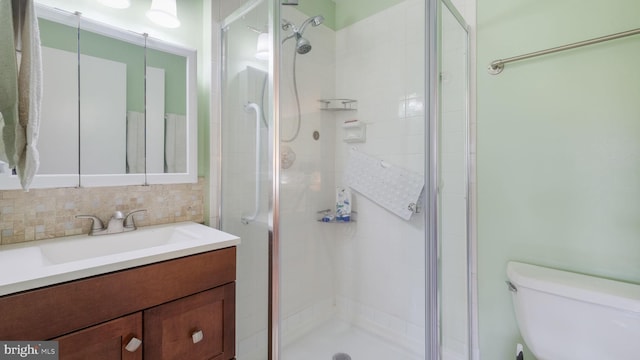 bathroom featuring decorative backsplash, vanity, an enclosed shower, and toilet