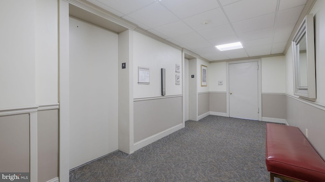 corridor with a paneled ceiling and dark carpet