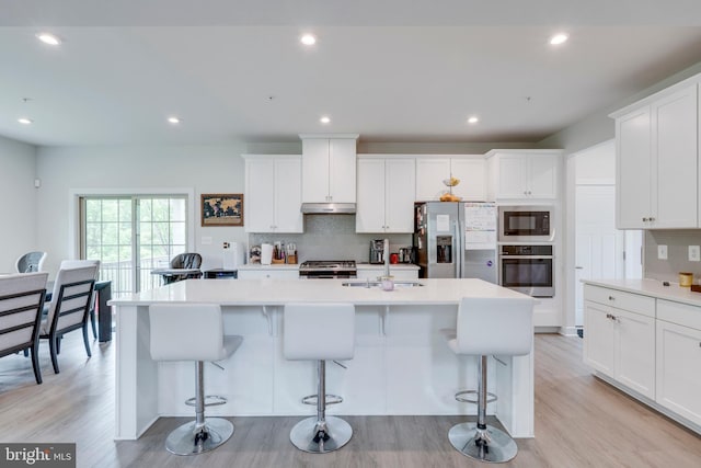 kitchen featuring stainless steel appliances, white cabinetry, and a kitchen island with sink