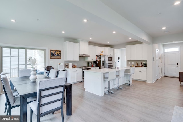 kitchen with sink, an island with sink, white cabinets, and appliances with stainless steel finishes