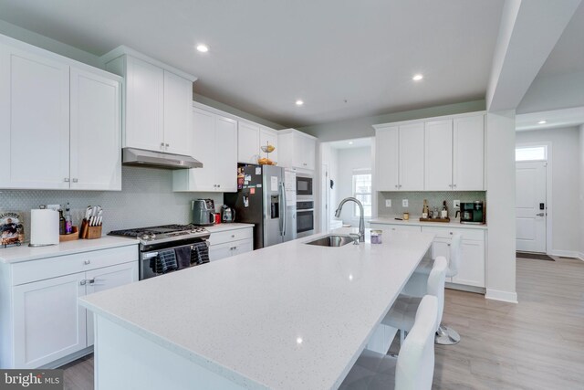 kitchen with a kitchen island with sink, white cabinets, and appliances with stainless steel finishes