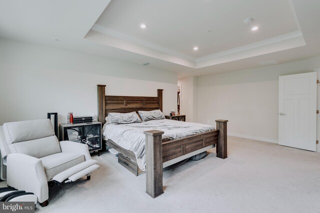 carpeted bedroom with a tray ceiling and ornamental molding