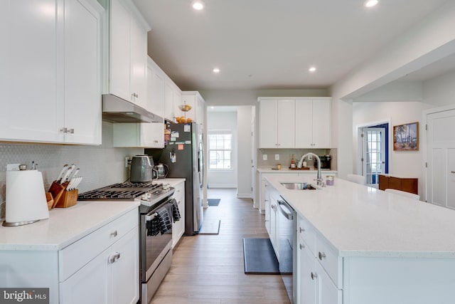 kitchen with stainless steel appliances, a kitchen island with sink, sink, and white cabinets