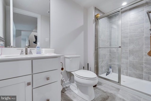 bathroom featuring vanity, a shower with shower door, and toilet