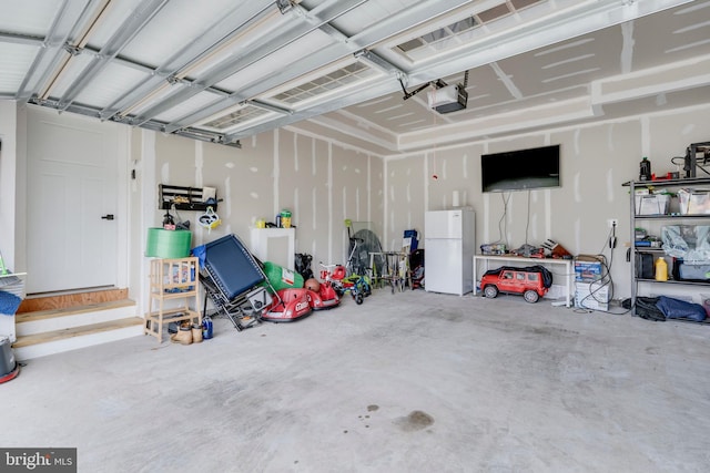 garage featuring a garage door opener and white fridge