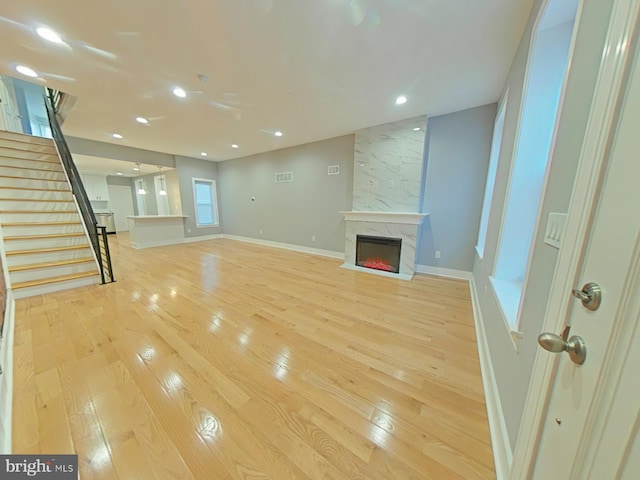 unfurnished living room with light wood-type flooring and a high end fireplace