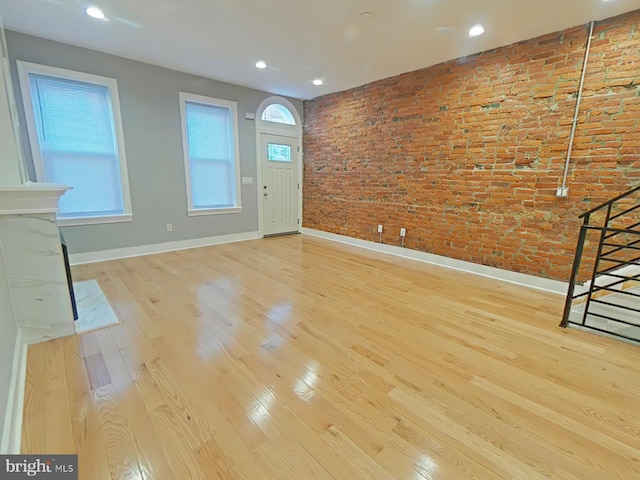 foyer entrance featuring brick wall and light hardwood / wood-style flooring