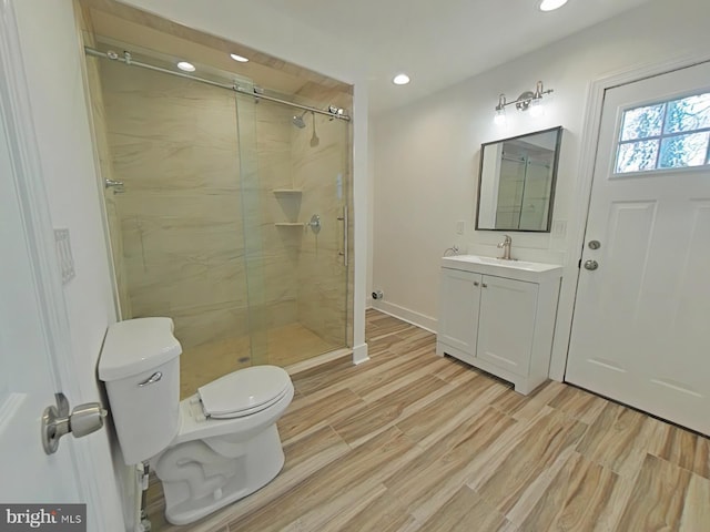 bathroom featuring vanity, wood-type flooring, a shower with shower door, and toilet