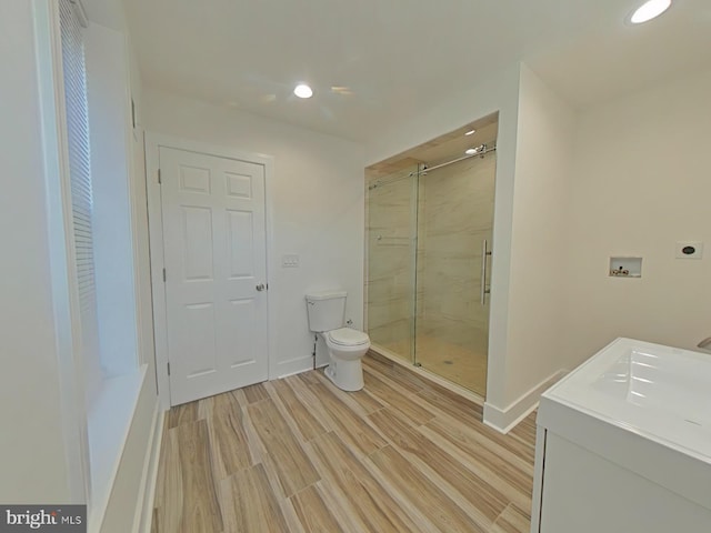 bathroom featuring hardwood / wood-style floors, vanity, a shower with door, and toilet