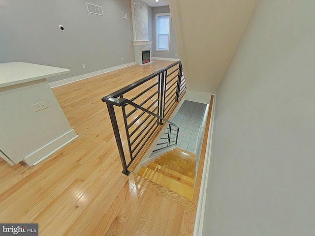 stairs with wood-type flooring and a premium fireplace