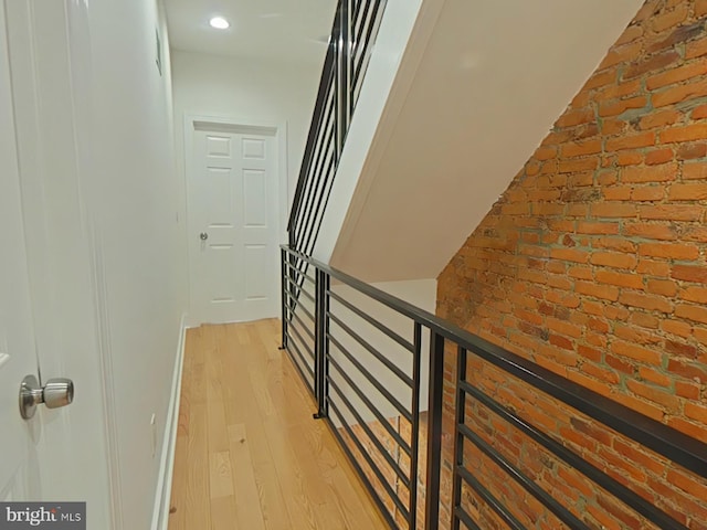 hall with brick wall and light wood-type flooring