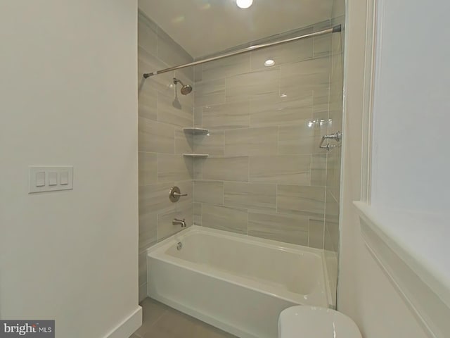 bathroom featuring toilet, tiled shower / bath combo, and tile patterned floors