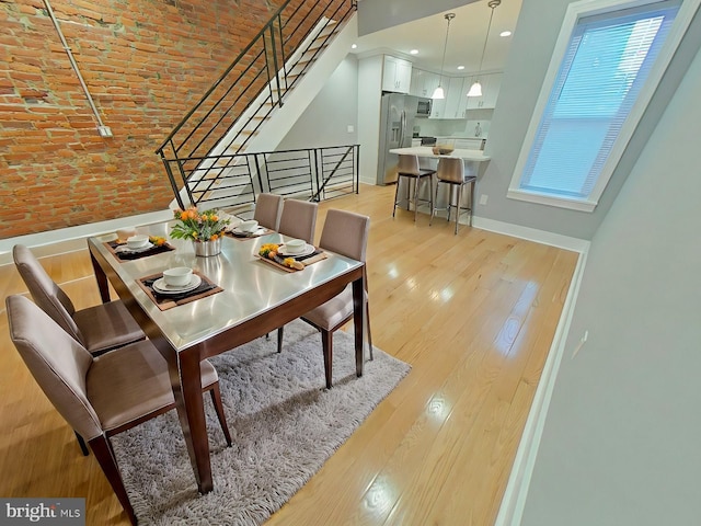 dining area featuring a towering ceiling, brick ceiling, and light hardwood / wood-style flooring