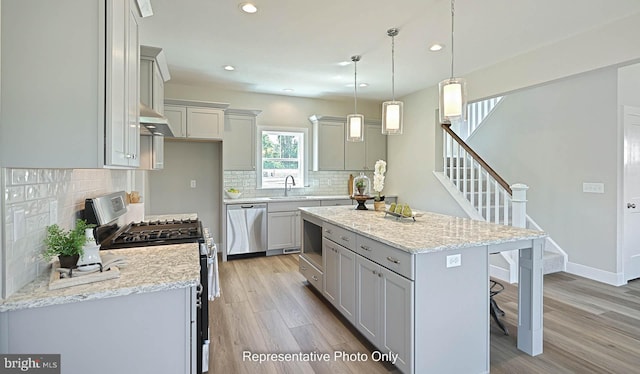 kitchen with a center island, hanging light fixtures, gray cabinets, light hardwood / wood-style floors, and stainless steel appliances