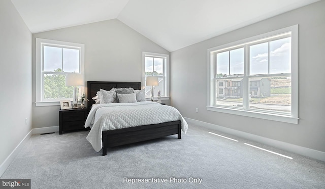 carpeted bedroom featuring vaulted ceiling and multiple windows