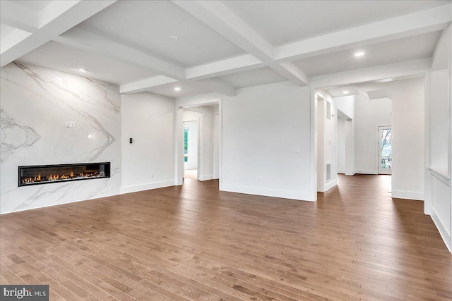 unfurnished living room featuring beam ceiling, a fireplace, and wood-type flooring