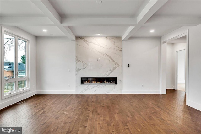 unfurnished living room with beam ceiling, coffered ceiling, and a premium fireplace