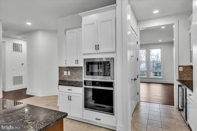 kitchen featuring oven, dark stone countertops, white cabinetry, and light tile patterned floors