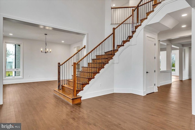 stairs featuring wood-type flooring and an inviting chandelier