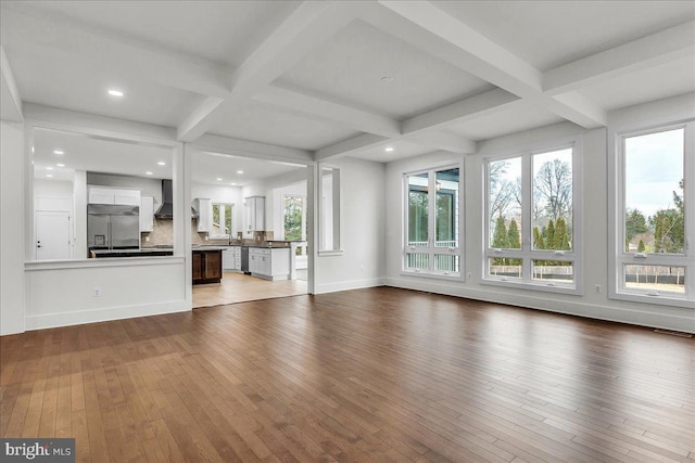 unfurnished living room featuring beam ceiling, coffered ceiling, and hardwood / wood-style floors