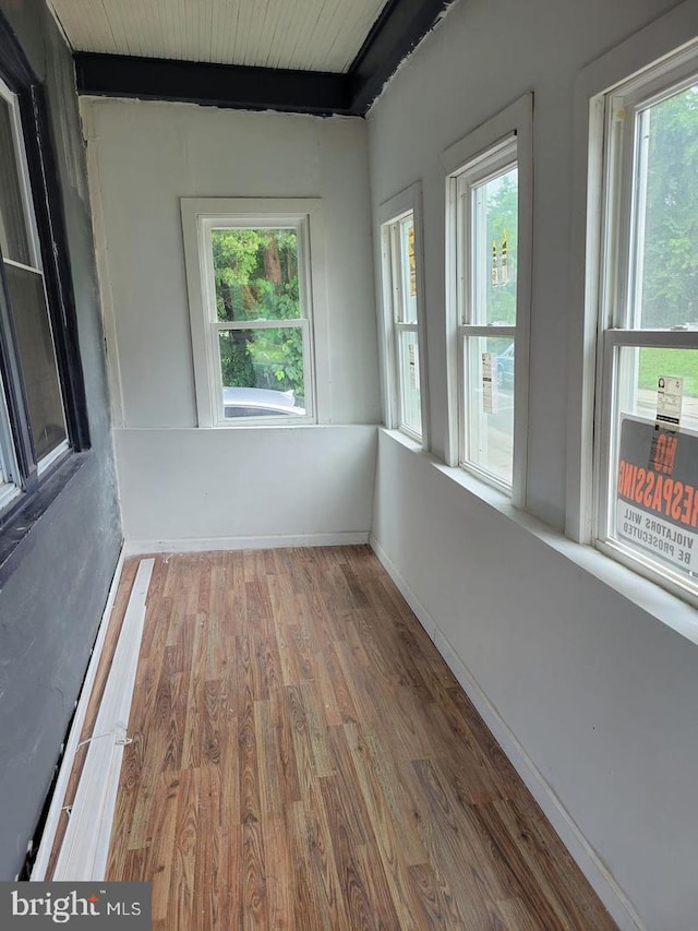 unfurnished sunroom featuring plenty of natural light and beam ceiling