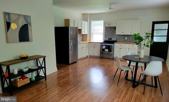 kitchen with white cabinetry, dark wood-type flooring, wood counters, tasteful backsplash, and appliances with stainless steel finishes