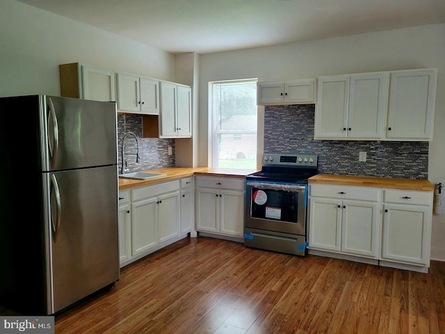 kitchen with light hardwood / wood-style floors, white cabinets, wooden counters, and appliances with stainless steel finishes