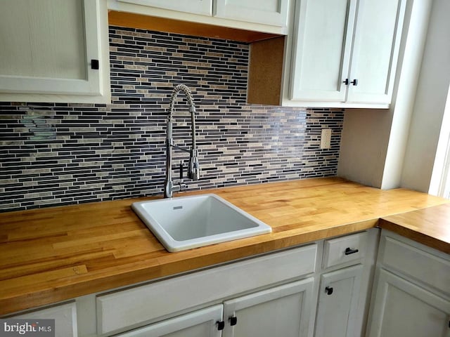 kitchen featuring wood counters, decorative backsplash, and sink