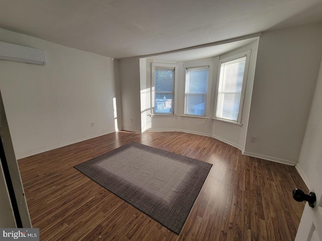 unfurnished room featuring a wall mounted AC and dark wood-type flooring