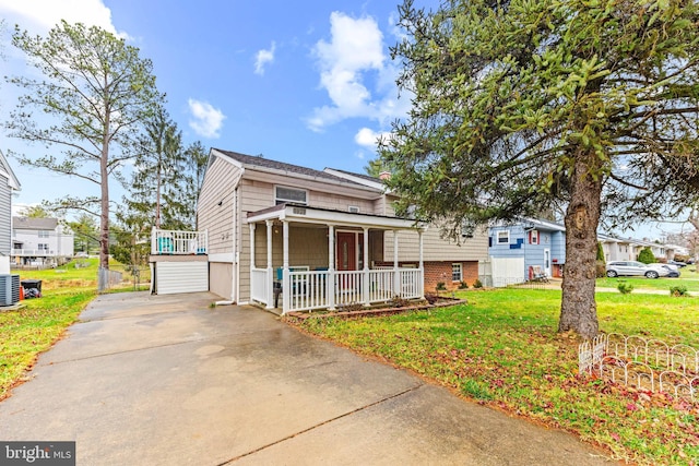 view of front of property with covered porch, central AC unit, a garage, and a front lawn