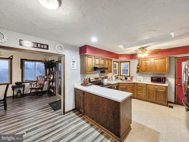 kitchen featuring kitchen peninsula, a textured ceiling, ceiling fan, sink, and stainless steel electric range