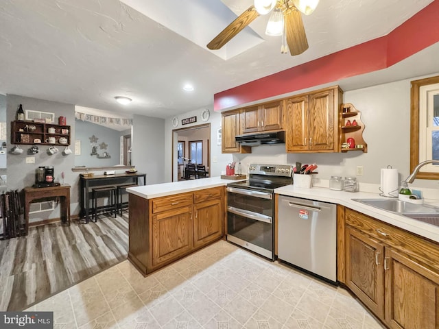 kitchen featuring sink, light hardwood / wood-style flooring, ceiling fan, kitchen peninsula, and stainless steel appliances