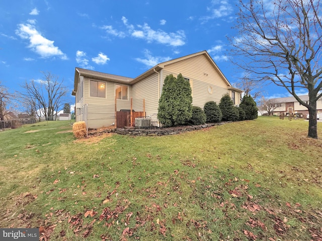 view of side of property featuring a yard and central AC