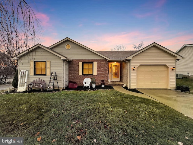 ranch-style house featuring a yard, central AC unit, and a garage