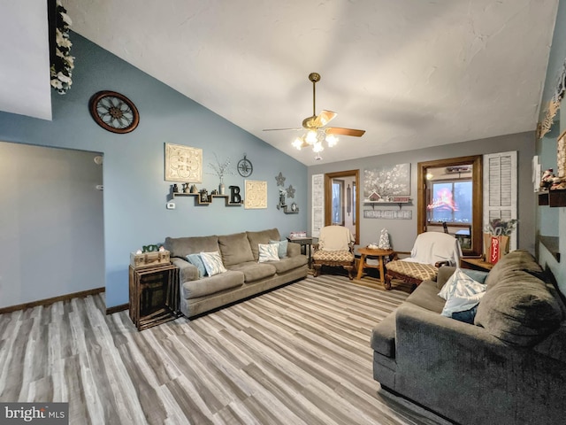 living room featuring ceiling fan, light wood-type flooring, and vaulted ceiling