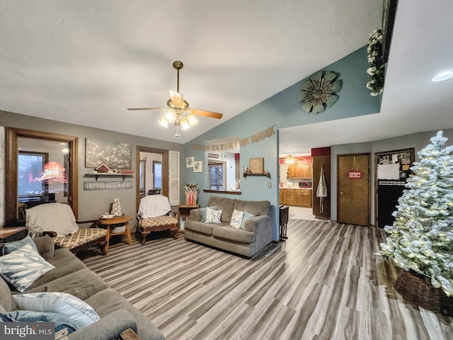 living room featuring ceiling fan, light hardwood / wood-style floors, and lofted ceiling