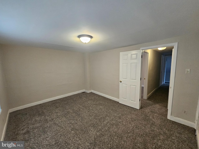 unfurnished room featuring dark colored carpet