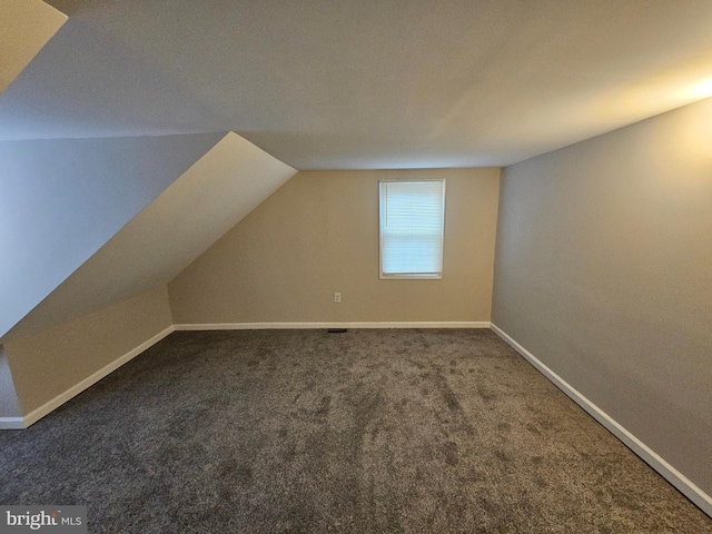 additional living space with dark carpet and lofted ceiling