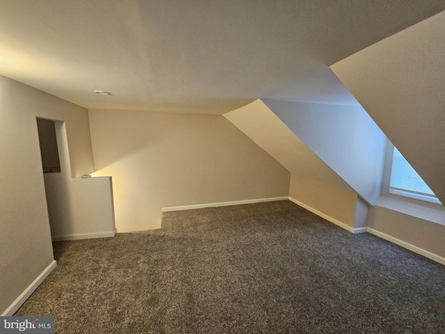 additional living space featuring dark carpet and vaulted ceiling