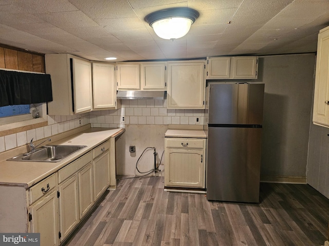 kitchen featuring dark wood-type flooring, cream cabinets, sink, stainless steel fridge, and tasteful backsplash