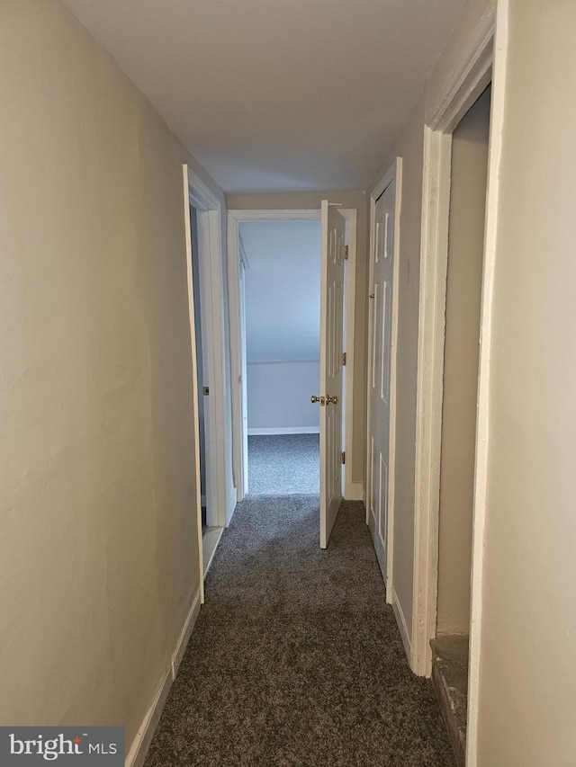 hallway featuring dark carpet